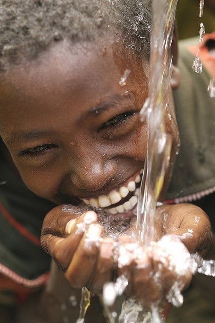 A child drinking water from cupped hands